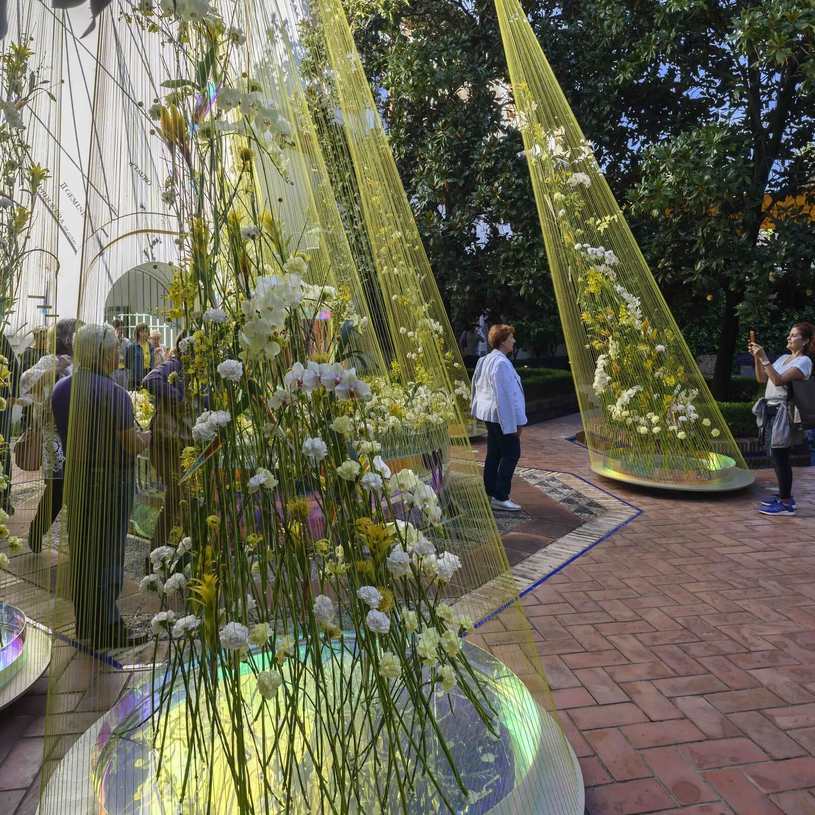 Patio con instalaciones de plantas y flores mientras el público pasea y hace fotos en exposicion de arte floral en Córdoba