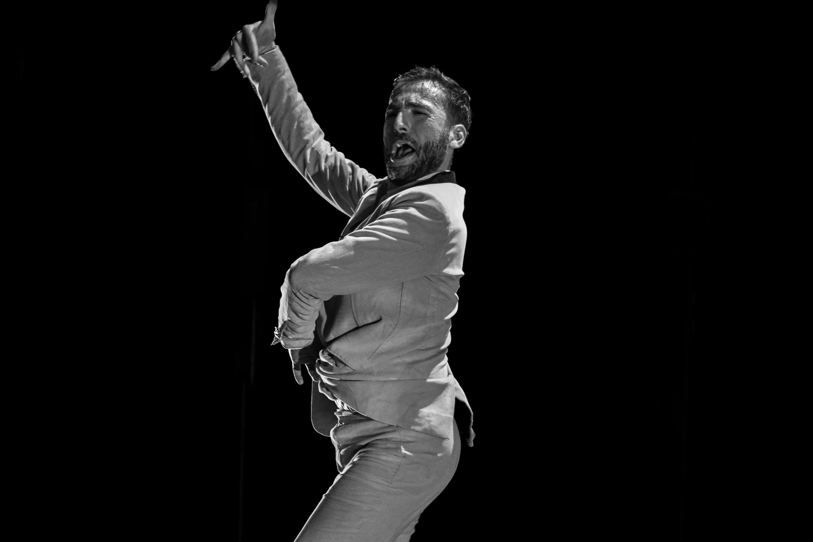 Bailaor de flamenco en una actuación apasionada en espectáculo de Flamenco en Madrid, capturado en blanco y negro con un fondo negro que resalta la intensidad y fuerza de su movimiento flamenco