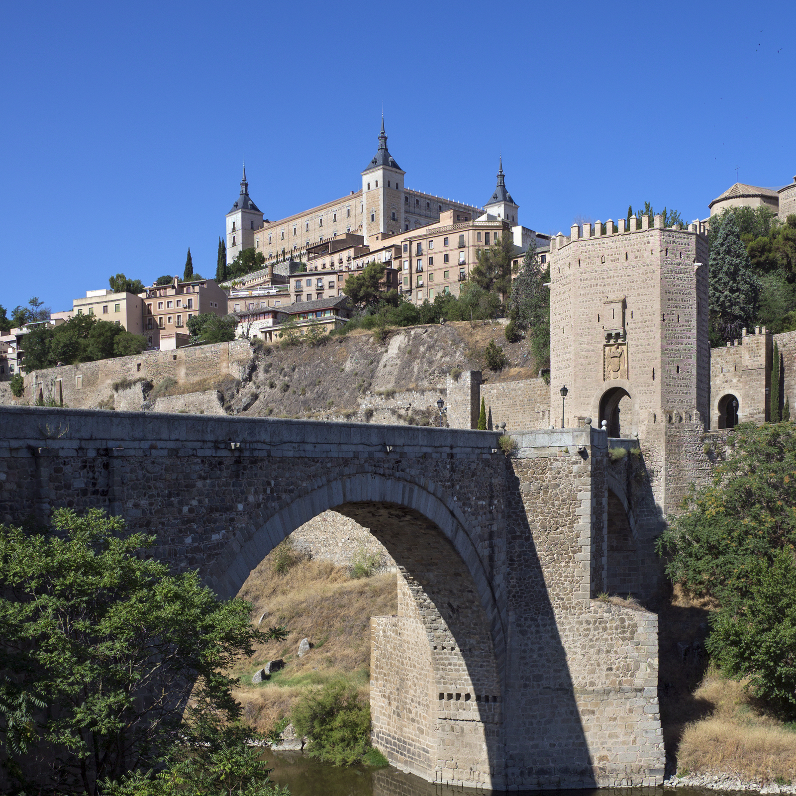 Vista del Alcázar de Toledo y el Puente de Alcántara, un emblemático paisaje histórico en la ciudad para escapada cultural en Toledo