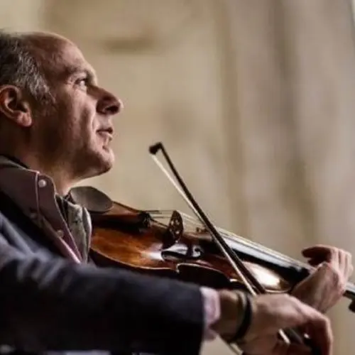 Músico tocando el violín en un ambiente íntimo y elegante, capturado en un momento de concentración y pasión